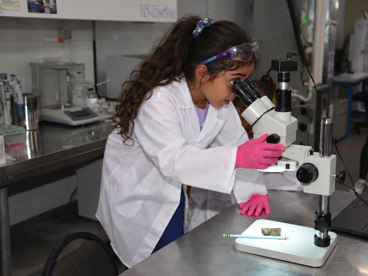 A MiLab student examining a sample under the microscope